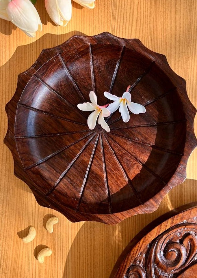 dark brown hand carved rosewood plate is kept on the table