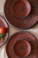A red hand painted dinner set with plate and bowl are decorated on the table