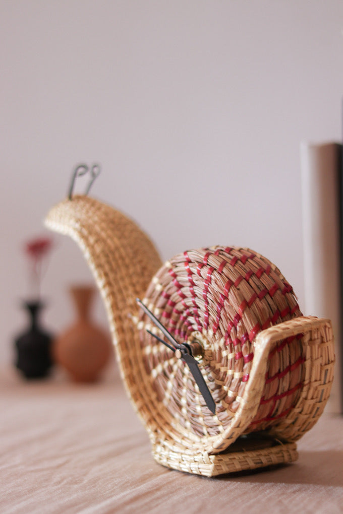 hand woven snail shaped table clock kept on table