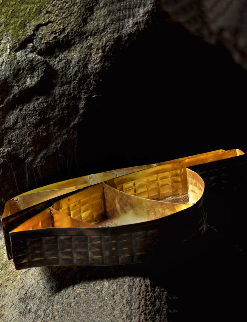 Brass hand embossed beetle shaped tray kept on the a rock