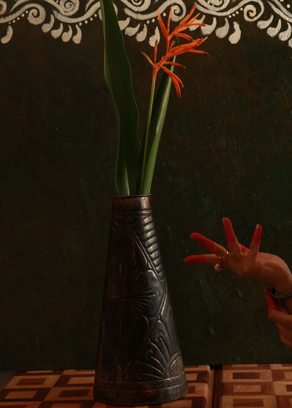 copper embossed vase decorated with flower kept on a table