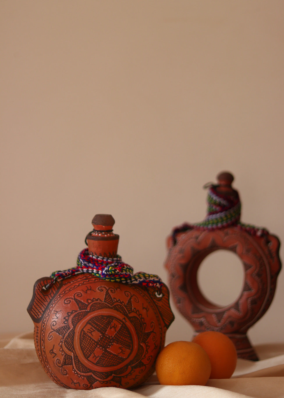 A red hand painted clay water bottle and red hand painted clay glass kept on the table