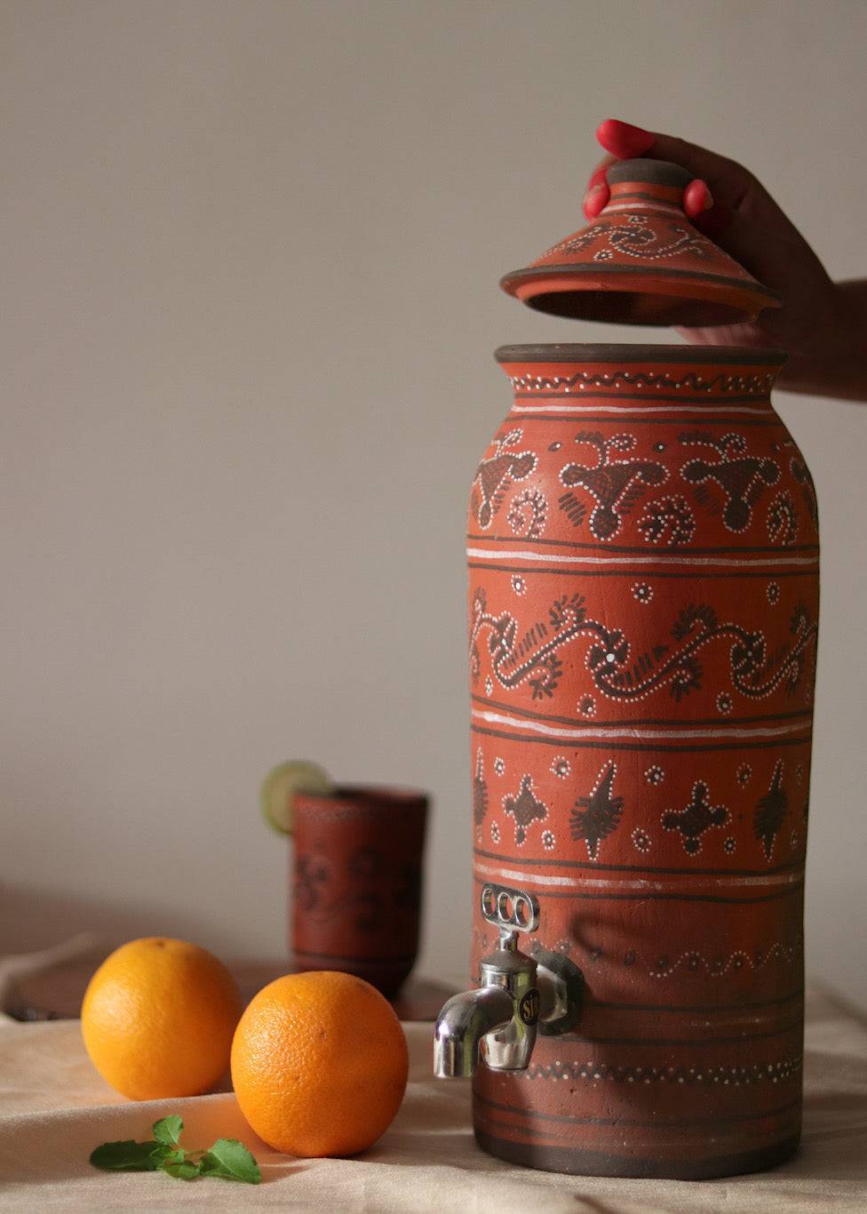 A red hand painted clay water dispenser kept on the table