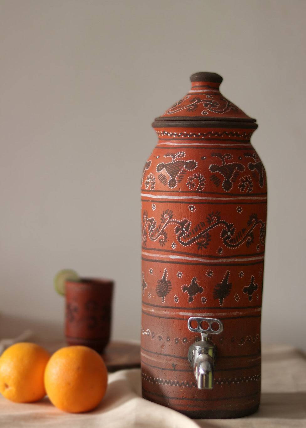 A red hand painted clay water dispenser kept on the table