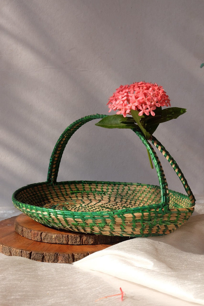 Green coloured sikki flower basket is decorated with flower and is kept on table