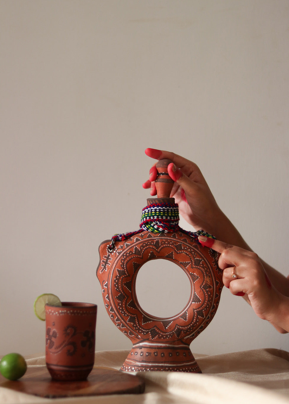 A red hand painted clay water bottle and red hand painted clay glass kept on the table