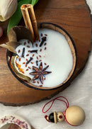 a hand poured coconut candle decorated with spices is kept on table