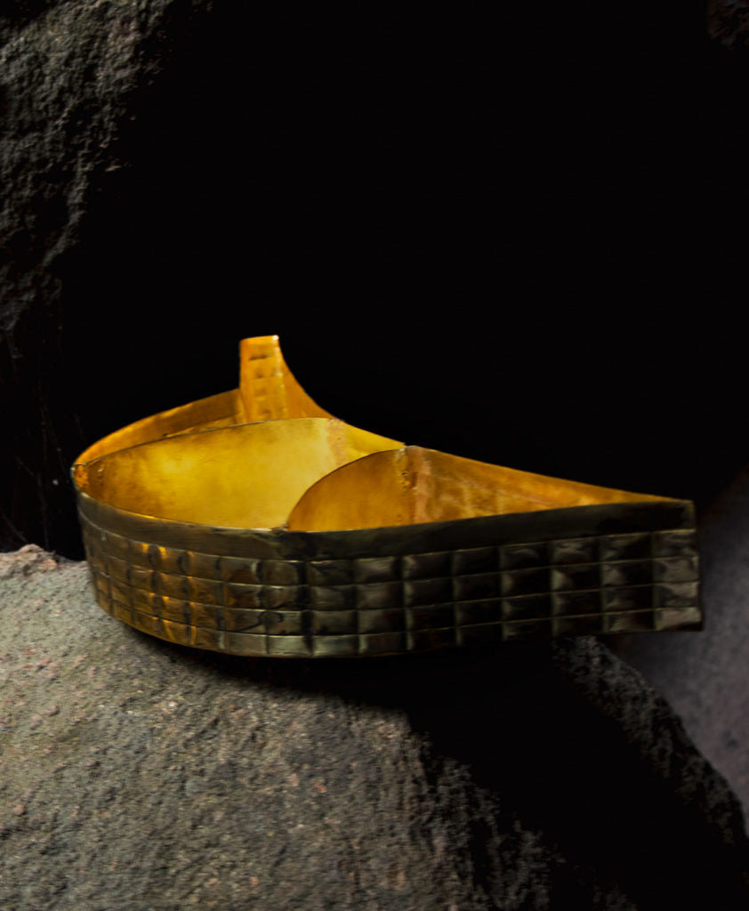 Brass hand embossed beetle shaped tray kept on the a rock