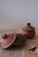a couple of red hand painted pottery serving bowls sitting on top of a table