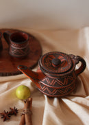 Red clay hand painted tea pot kept on the table along with red hand painted clay cup