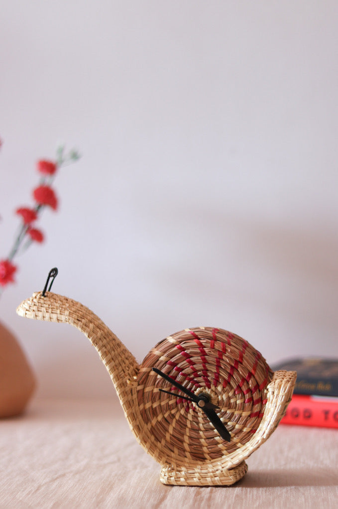 hand woven snail shaped table clock kept on table 