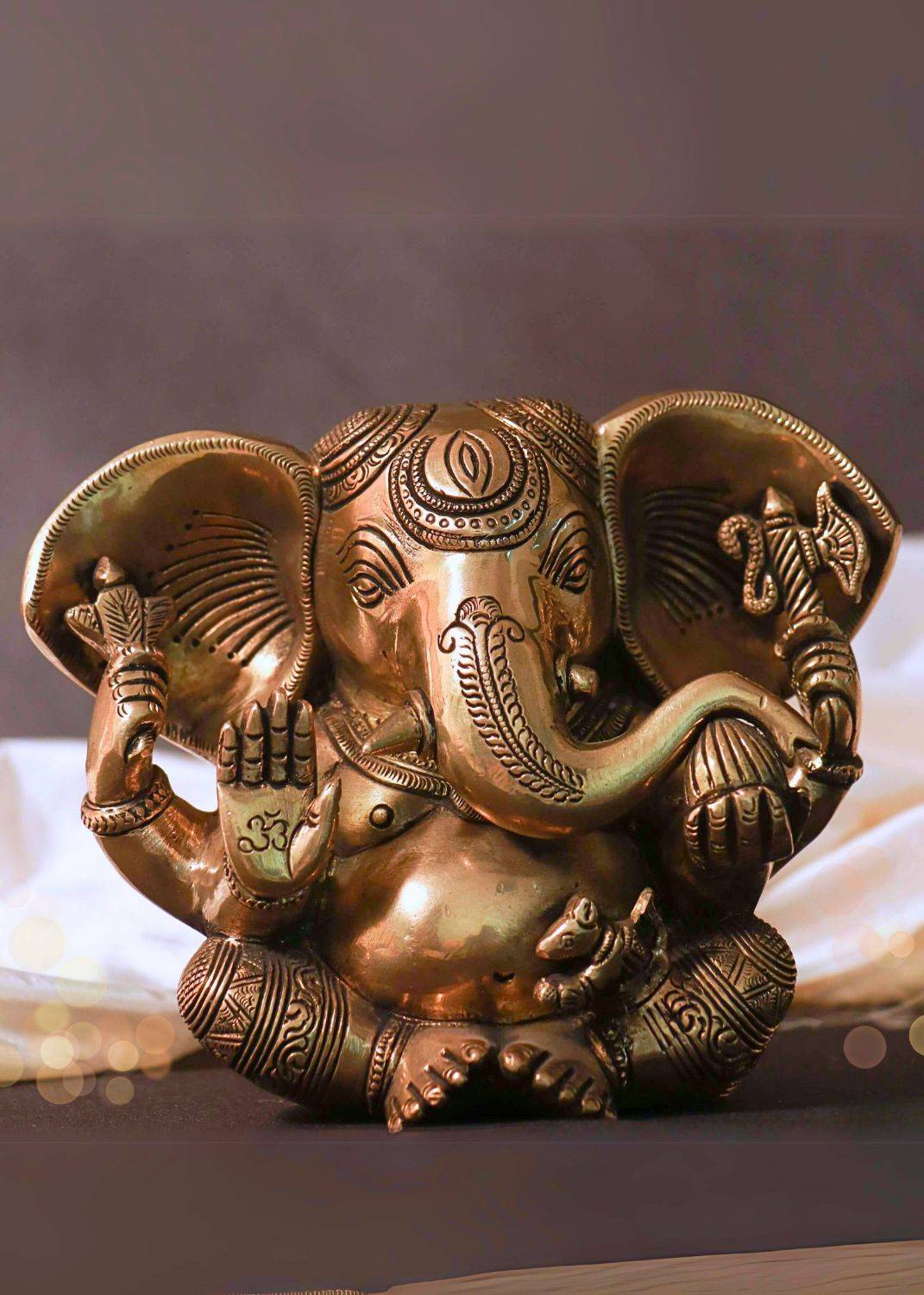 Decorative brass elephant figure with intricate designs on a blurred background