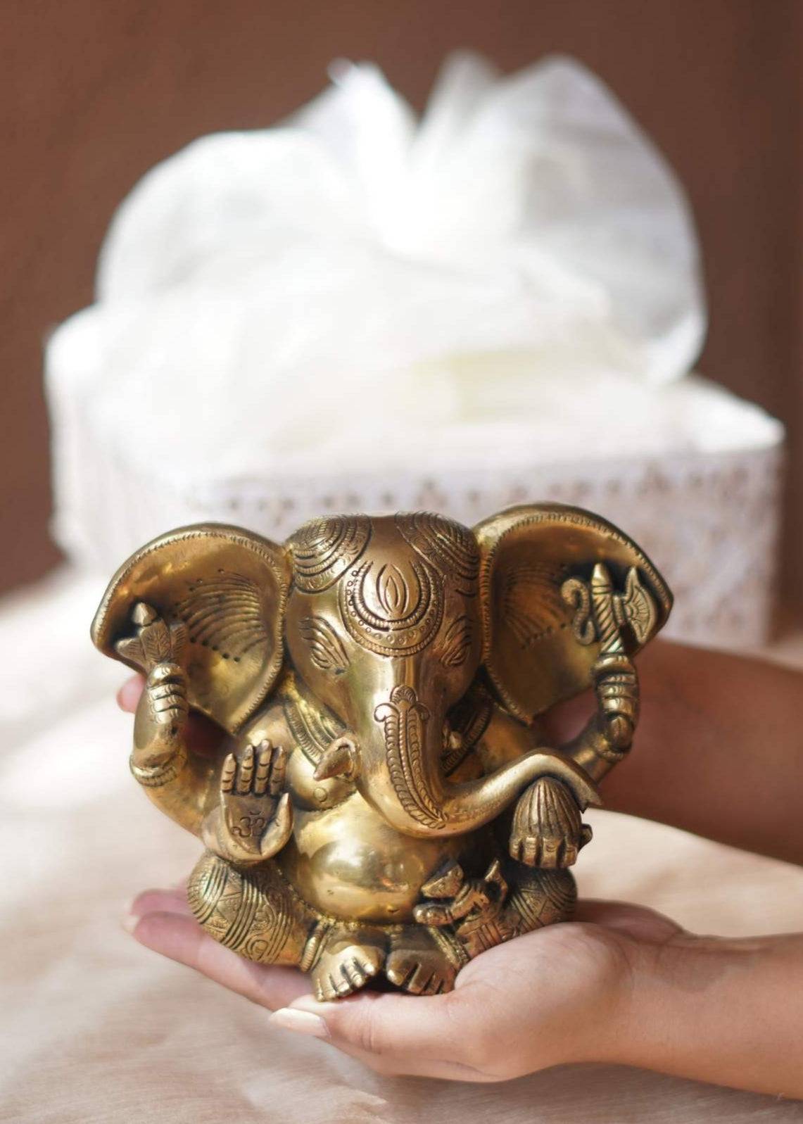 Brass elephant figurine held in a hand with a blurred white object in the background