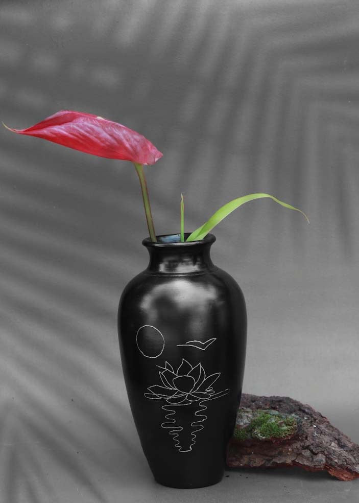 black clay vases with silver inlay motifs are kept on the table with red flower decorated in it.