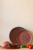 A red hand painted dinner set with plates kept on the table