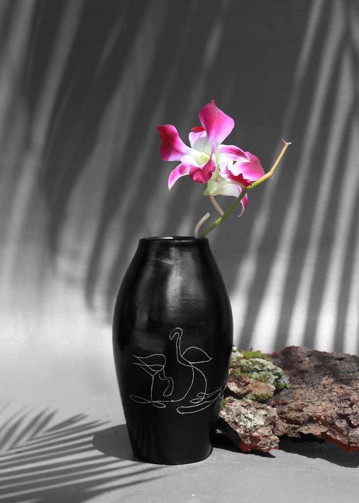 black clay vases with silver inlay motifs are kept on the table with purple flower decorated in it.