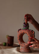 A red hand painted clay water bottle and red hand painted clay glass kept on the table