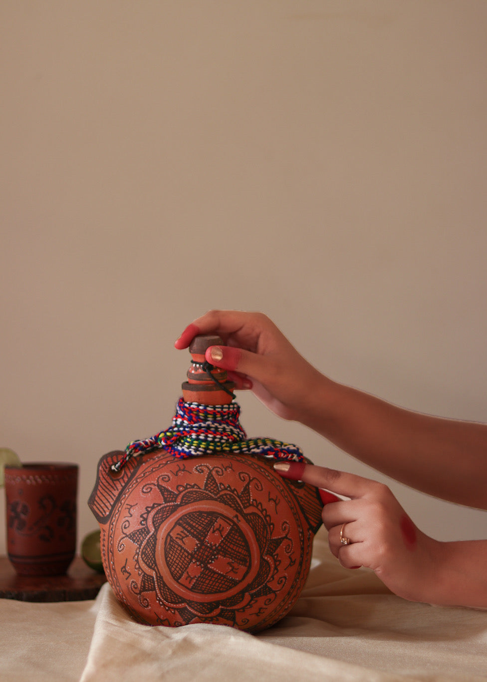 A red hand painted clay water bottle and red hand painted clay glass kept on the table