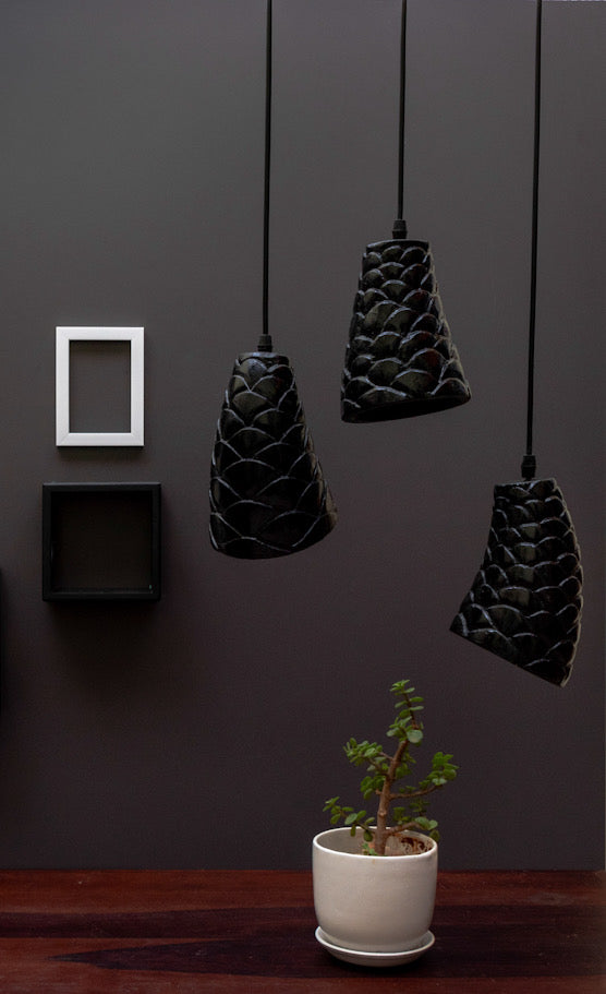 black stone sculpted pendant light is hanging above a table