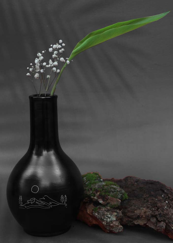 black clay vases with silver inlay motifs are kept on the table decorated with white flower