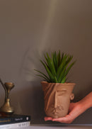 A woman shaped white planter is held in the hand of a woman 