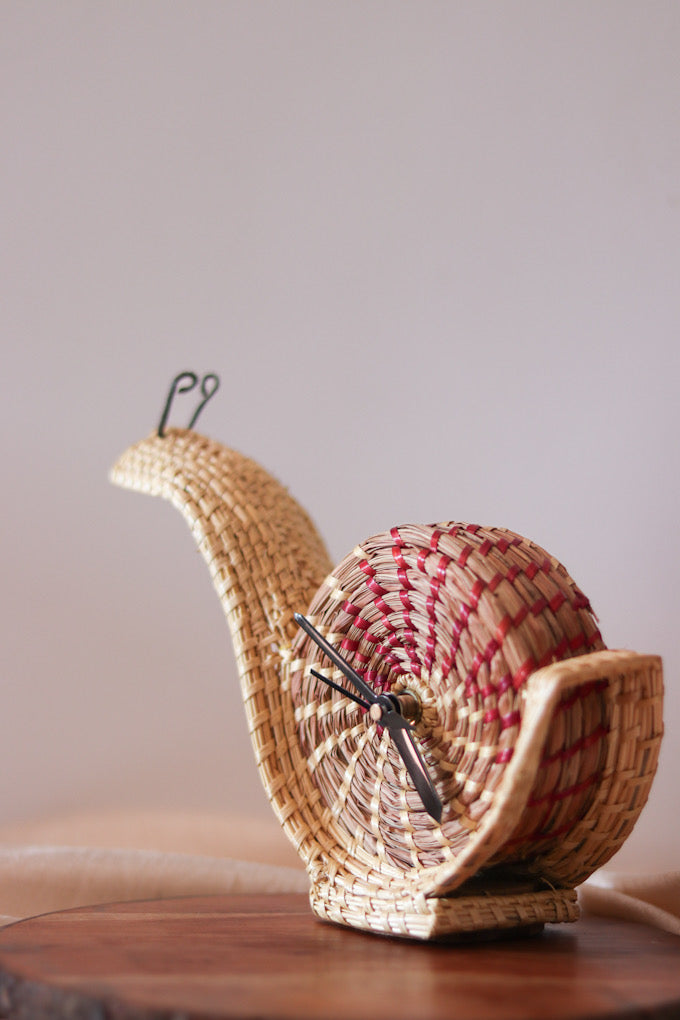 hand woven snail shaped table clock kept on table 